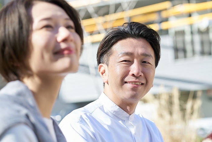 Japanese man looking at woman with gentle expression outdoors (People)