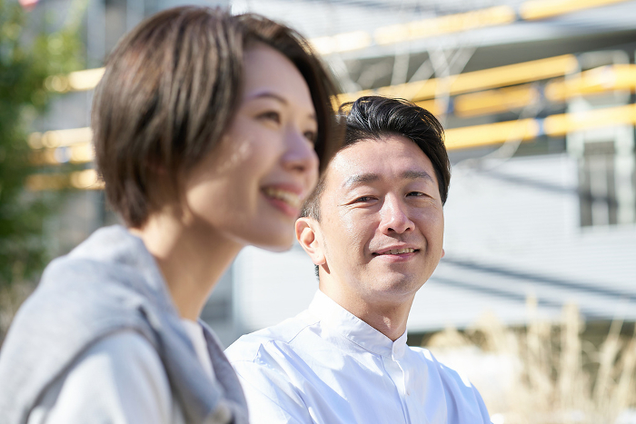 Japanese man looking at woman with gentle expression outdoors (People)