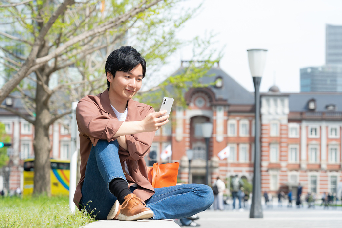 Young Japanese man looking at his smartphone (People)