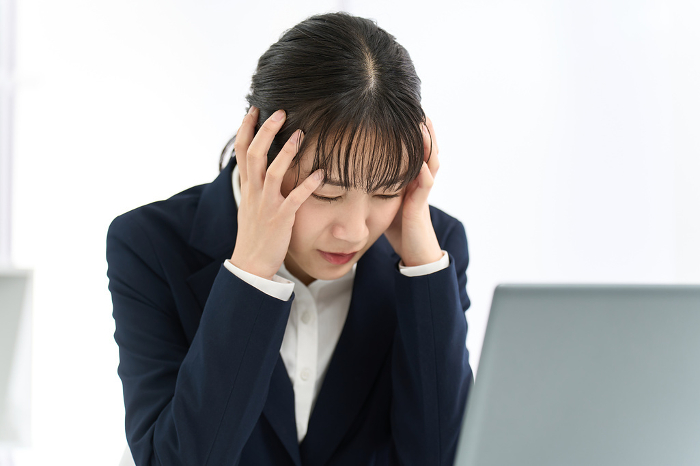 Japanese businesswoman with her head in front of computer (Female / People)