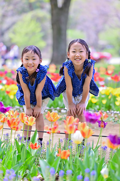 Sisters laughing with their hands on their knees in a tulip field