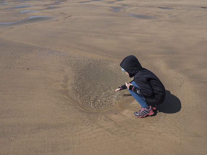 Child plays at a tide pool on the beach in Wales Child plays at a tide pool on the beach in Wales, by Zoonar Reiner Pechma