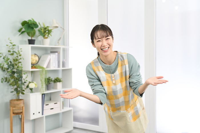 A Japanese woman in an apron welcoming the guests (People)