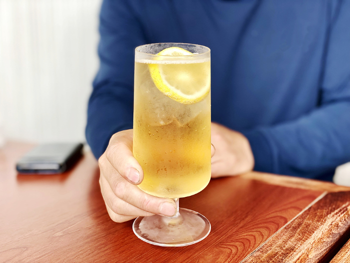 Man's hand holding a glass of lemon sour