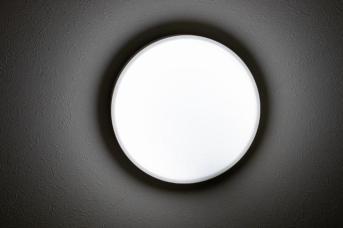 Circular light fixture glowing on the ceiling of a dark room
