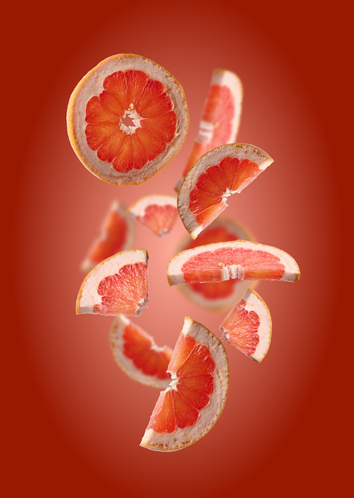 Various pieces of ripe grapefruit on a red background, fruit slices levitate Various pieces of ripe grapefruit on a red background, fruit slices levitate