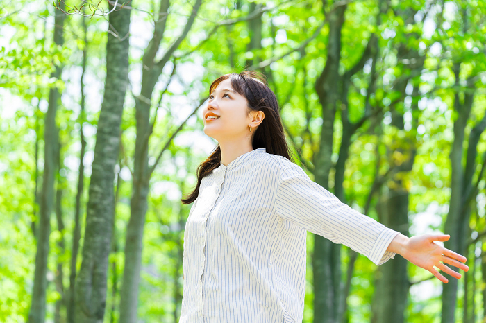 A young Japanese woman taking a deep breath amidst the greenery (People)