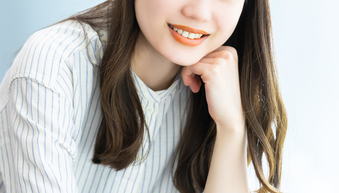 Young Japanese woman smiling and resting her cheekbones (People)