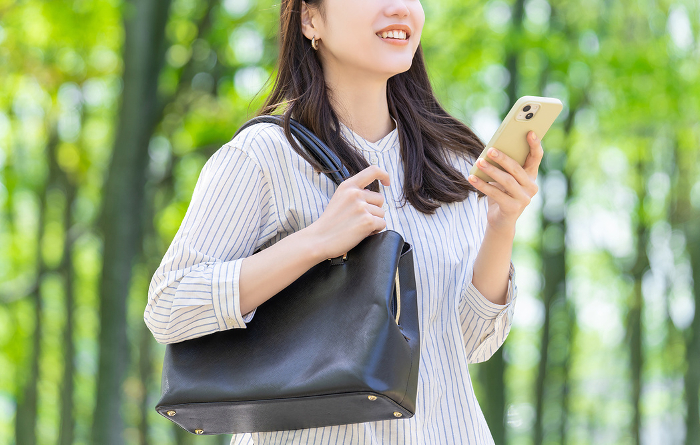 Smiling Japanese businesswoman operating a mobile phone (Female / People)