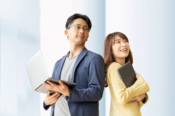 Image of a male and female Japanese businessman/teamworker standing with a computer and tablet (People)