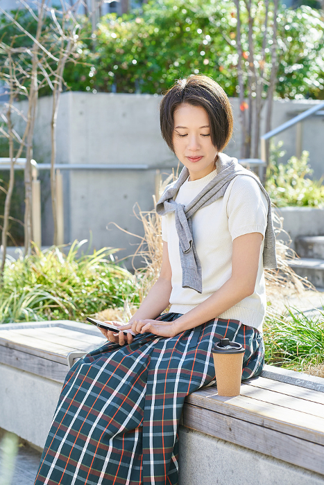 Japanese woman operating smartphone while drinking coffee (People)