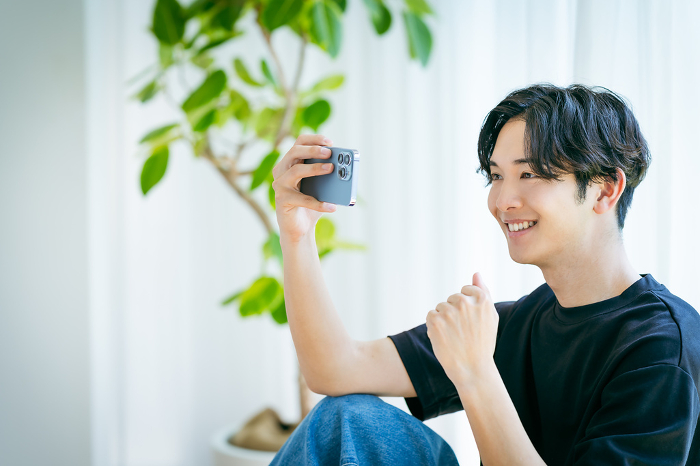 Young Japanese man operating a cell phone (People)