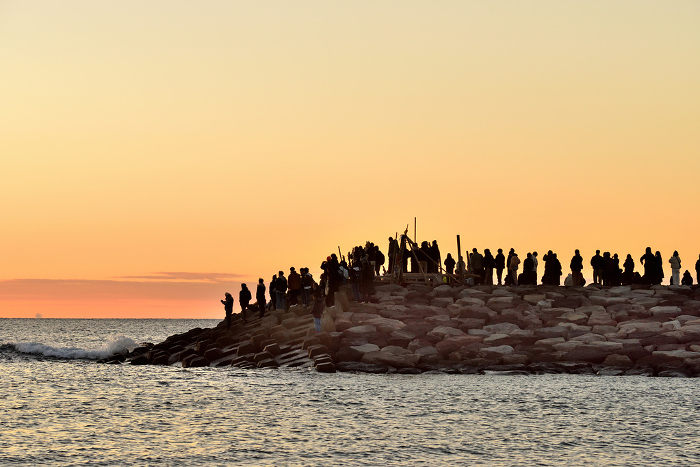 Silhouettes of people greeting the first sunrise on the beach