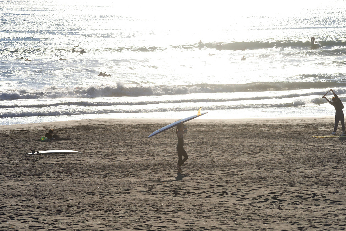 Surfer walking on the beach under the afternoon sun