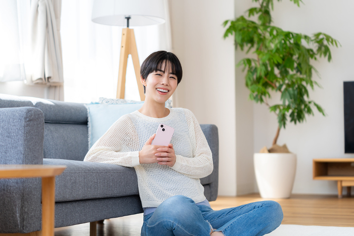 Japanese woman operating a smartphone in her room (People)