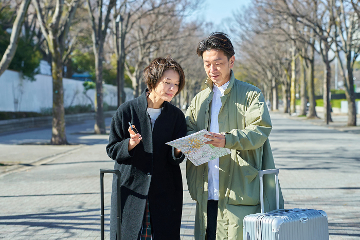 Japanese man and woman lost with suitcases (People)