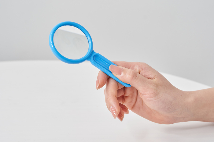 Woman's hand holding magnifying glass and white background
