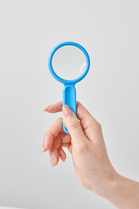 Woman's hand holding magnifying glass and white background
