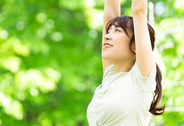 Smiling Japanese woman stretching in the green (People)