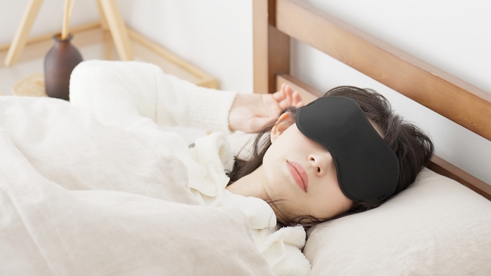 Japanese woman sleeping with eye mask in a bright room (People)