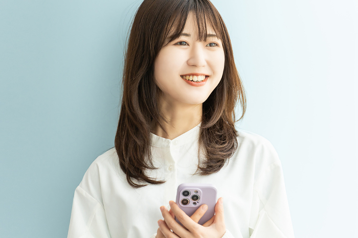 Smiling Japanese businesswoman holding a smartphone (Female / People)