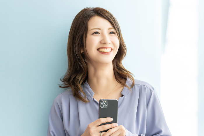 Smiling Japanese businesswoman holding a cell phone (Female / People)