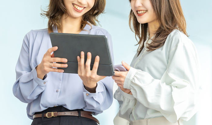 Two Japanese businesswomen talking while looking at a tablet (Female / People)