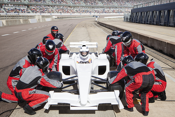   Pit crew in perfect sync servicing a race car on the track.