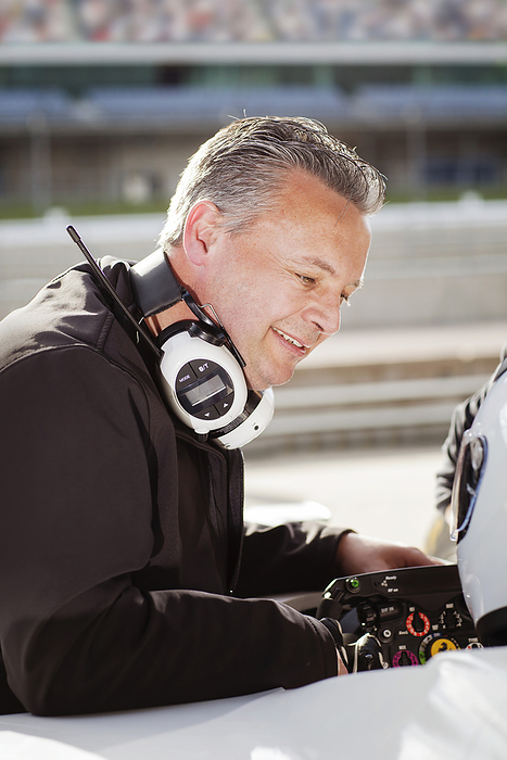 Focused man at a racing event with headphones monitoring performances