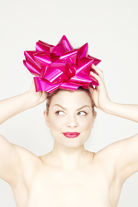 Playful portrait of a woman humorously wearing a giant pink bow on her head