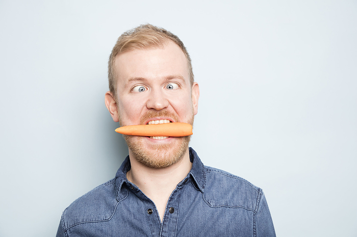 Young man eating carrot