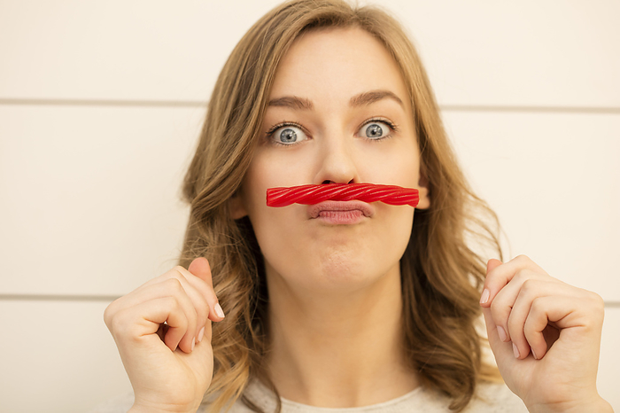 Young woman with red liquorice moustache