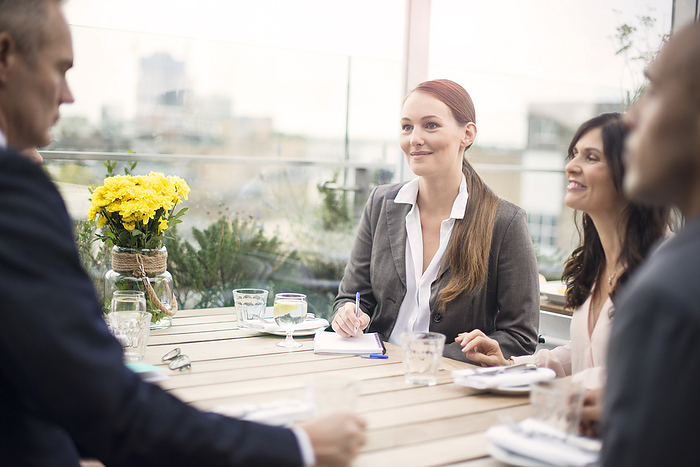 Young businesswoman during meeting at restaurant with colleagues