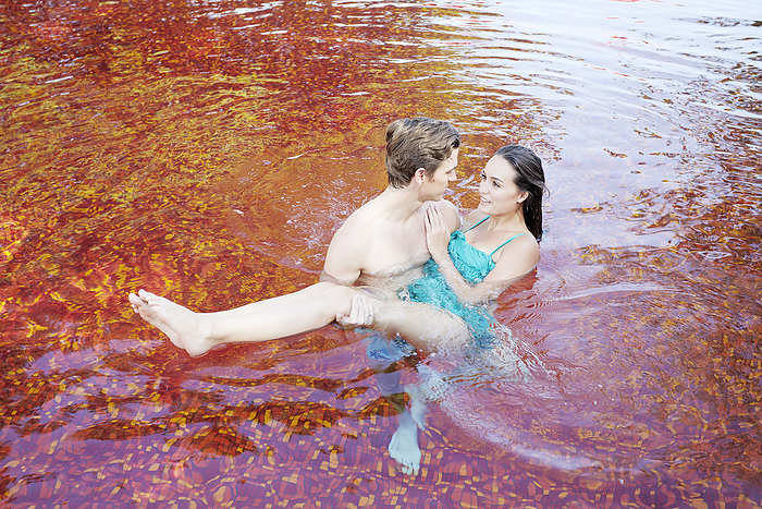 Young couple embracing at red swimming pool