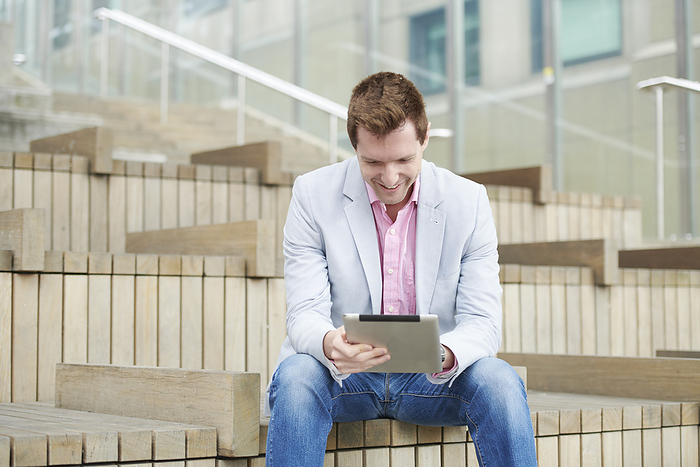 Mid adult man using digital tablet on staircase