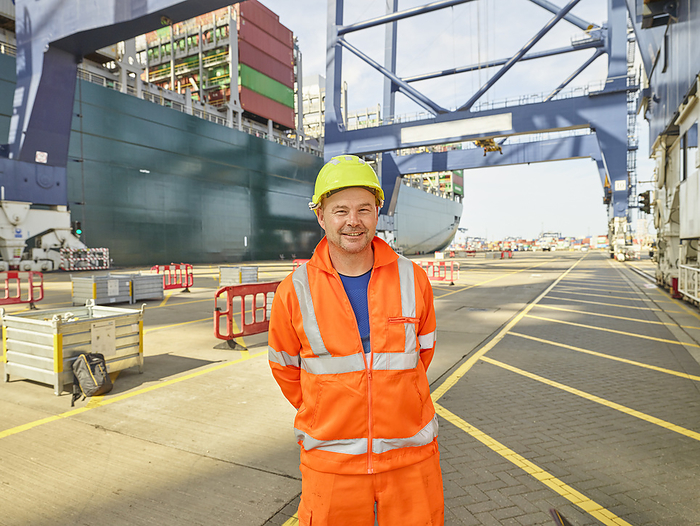 Smiling dock worker in reflective clothing and hard hat