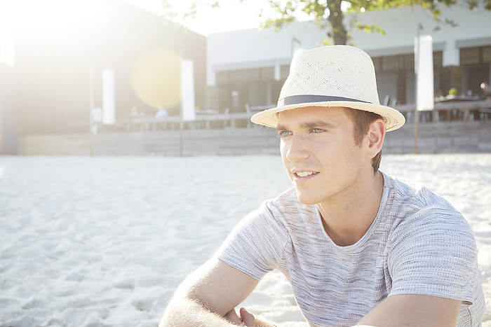 Young man wearing straw trilby hat on beach
