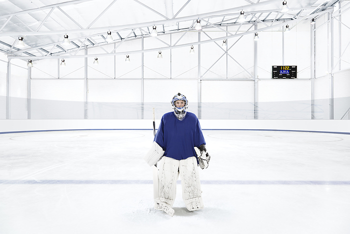 Ice hockey goalkeeper wearing a blue uniform at an ice rink