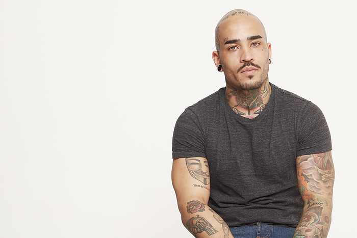 Confident man with tattoos posing against a white background