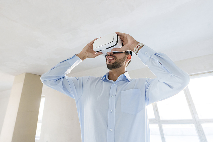 Man wearing virtual reality simulator and inspecting future renovation designs of new house