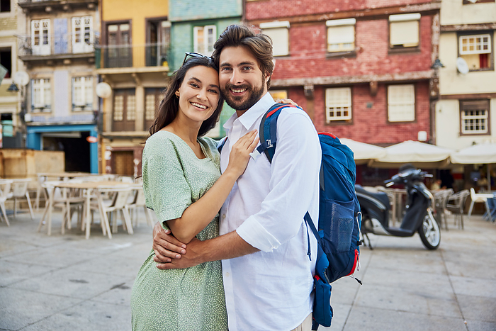 Smiling young couple standing together in front of buildings