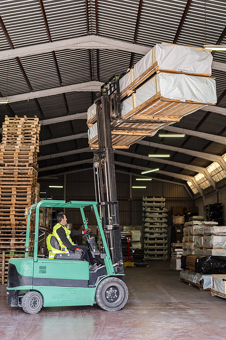 Forklift worker carrying wood pallets at warehouse
