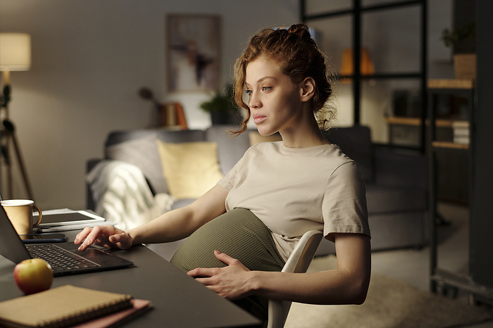 Pregnant woman working on laptop from home