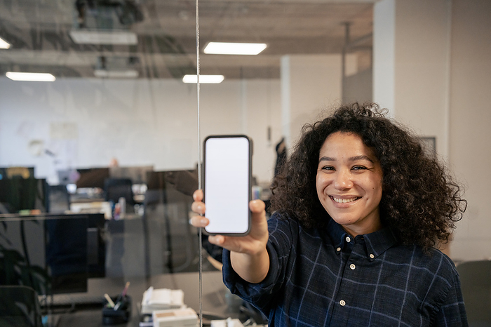 Happy businesswoman showing smart phone in office
