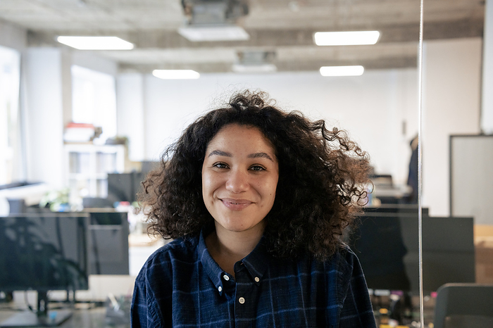 Smiling businesswoman with curly hair in office