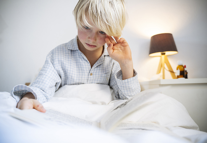 Boy reading book in bedroom at home