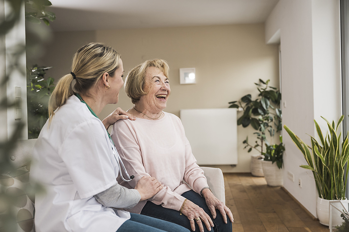 Smiling doctor taking care and giving advice to senior woman at home