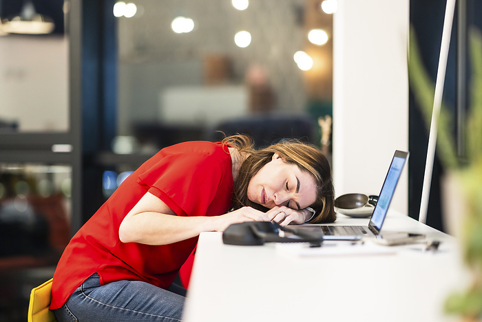 Tired businesswoman resting near laptop at desk in office