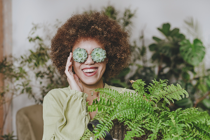 Smiling woman wearing echeveria eyeglasses near plant at home