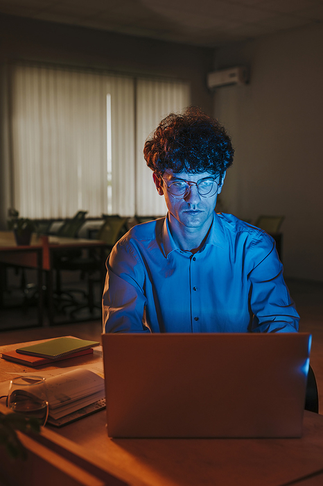Businessman working on laptop in office late at night